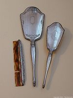 Full view of the antique Birks sterling silver vanity set pieces: mirror, brush, and comb on white background.