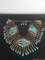 Front view of the large turquoise chest piece necklace showing central diamond pendant and side triangular sections with linked chains and turquoise teardrop charms.