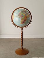 Full front view of the vintage floor standing globe showing the globe and stand.
