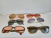 Top front view showing all six pairs of sunglasses arranged in two rows on a clear surface.