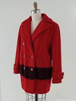 Front view of the red Hudson Bay style double-breasted wool coat with black waist band and button details on cuffs.