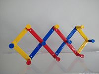 Side view of the accordion coat rack showing yellow, red, and blue color sections and pegs.