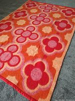 Angled view of entire blanket laid flat showing repeating multicolored floral pattern and edge binding.