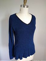 Front left side view of a blue v-neck sweater on a dress form showing ribbed knit texture and scalloped hem