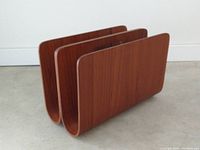 Overall side view of vintage bent teak magazine rack showing its three vertical compartments and smooth curved design.