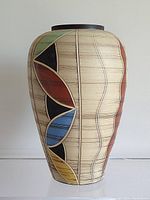 Front side of the vase showing the colorful leaf-like abstract pattern and vertical lines on beige background.