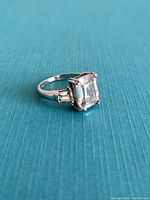 Side angled view showing the large rectangular clear gemstone and side stones on a sterling silver band.