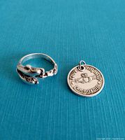 Sterling silver adjustable dolphin ring and Irish style pendant on blue background