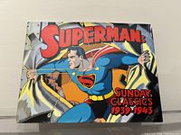 Front cover of hardcover Superman coffee table book titled 'Superman Sunday Classics 1939-1943' showing classic comic book style illustration of Superman.