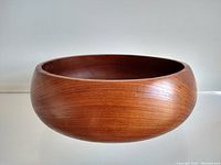 Side view showing the curved sculptural form and smooth finish of the teak bowl.