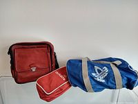 Three vintage Adidas gym bags laid out showing front and side views.