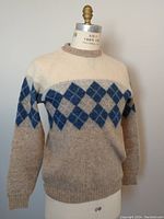 Front view of vintage wool argyle sweater on mannequin showing cream upper body, blue and beige argyle pattern, and beige lower body.