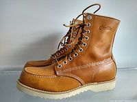 Side view of the pair of tan leather gorilla moc toe work boots with white sole and stitched moc-toe detail.