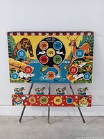 Full front view of the game board showing colorful wildlife and point zones with metal legs.