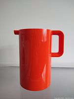 Front side view of the orange melamine pitcher showing handle and body shape.