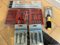 Photo of a 44 piece drill accessory set in plastic case along with two 3-piece socket adaptor sets and a small screwdriver, all new in packaging.