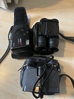 Yashica T4 camera next to both binoculars on table