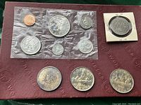 Sealed 1963 coin set in plastic envelope, three loose silver dollars (1953, 1962, 1964) displayed below, and one 1971 dollar in a 2×2 paper holder at top right