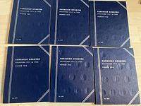 Six closed blue folders arranged in two rows of three on wood surface