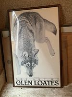 Framed print of a wolf by Glen Loates leaning forward, visible brown wooden frame, with text 'THE ART OF GLEN LOATES' at bottom