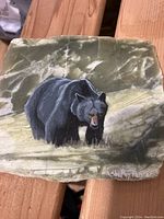 Close-up of the painting showing the black bear and signature on marble