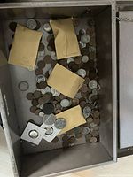 Open view of metal strong box interior containing loose coins, four manila envelopes, and two cardboard flips.