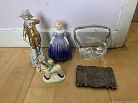Five items on floor: three figurines, glass sculpture, and silver card case.