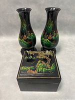 Pair of black lacquer vases with detailed hand painted colorful Chinese landscape scenes and rectangular lacquer box with similar hand painted scene on lid.