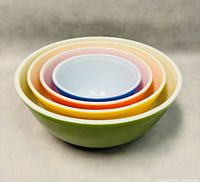 Four mixing bowls nested inside each other showing colored exteriors and white interiors