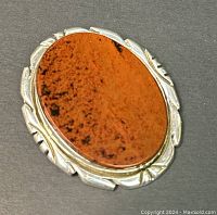 Close-up front angle of the oval brooch showing the agate stone and silver decorative frame.