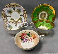 Three teacups and two saucers displayed showing front and interior designs