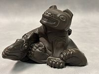 Side view of the bronze sculpture displaying the detailed carved patterns on the animal and fish.