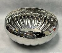 Front angle view of the polished stainless steel serving bowl showing interior and exterior fluted design.