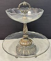 Front view of the vintage double-tier serving piece showing both glass plates connected by silver plated detailed column and base, top handle visible.