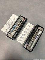 Top view of both Parker pens in original black boxes with Parker logos, open showing pens and cartridge compartments.