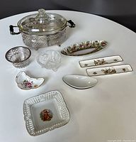 Full view of all serving pieces on table arranged for lot overview, showing all types of items, including silver-plated, ceramic, and glass items.