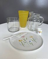All six items arranged on a white table against a gray background showing platter, pie server, two glass vases, vintage glass pitcher, and small ceramic cup.