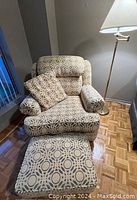 Front view of armchair with matching pillow and ottoman in yellow and grey circular pattern chenille fabric, floor lamp visible in background.
