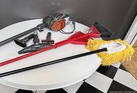 Whole lot showing Shark vacuum with attached cord, 3 vacuum attachments, Vileda broom and dustpan, and dust mop