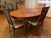 Oval wood dining table with 4 matching chairs. Table surface has visible wood grain and polished finish.