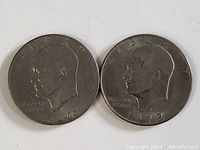 Obverse sides of two Eisenhower silver dollar coins dated 1976 and 1972 showing President Eisenhower's profile and inscriptions.