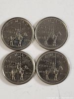 Four Canadian 1974 quarters with Mountie design on horseback and flag, showing wear and some tarnish.