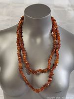 Full view of the long amber necklace displayed doubled over the neck form.