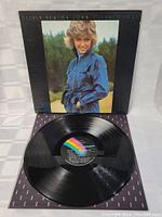 Photo shows front cover of Olivia Newton-John Clearly Love vinyl LP record with artist photo in denim jacket outdoors.