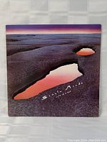 Front cover of Simple Minds Life In A Day vinyl LP showing scenic rock formation and water reflections with album title and band name.