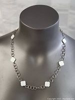 Front view of the sterling silver necklace with mother of pearl flower-shaped inlays and circular chain links.