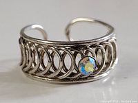 Front angled close-up of the sterling silver ring showing the intricate looped design and crystal accent