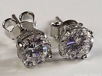 Close-up front angled view of the sterling silver stud earrings with clear round stones showing prong settings and butterfly backs.