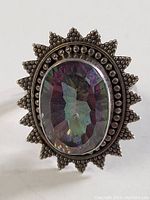 Front view showing the large faceted oval purple-blue stone in a detailed sterling silver sunburst setting.