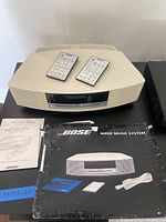 Bose Wave Music System with two remote controls on top, original manuals and software update disc.